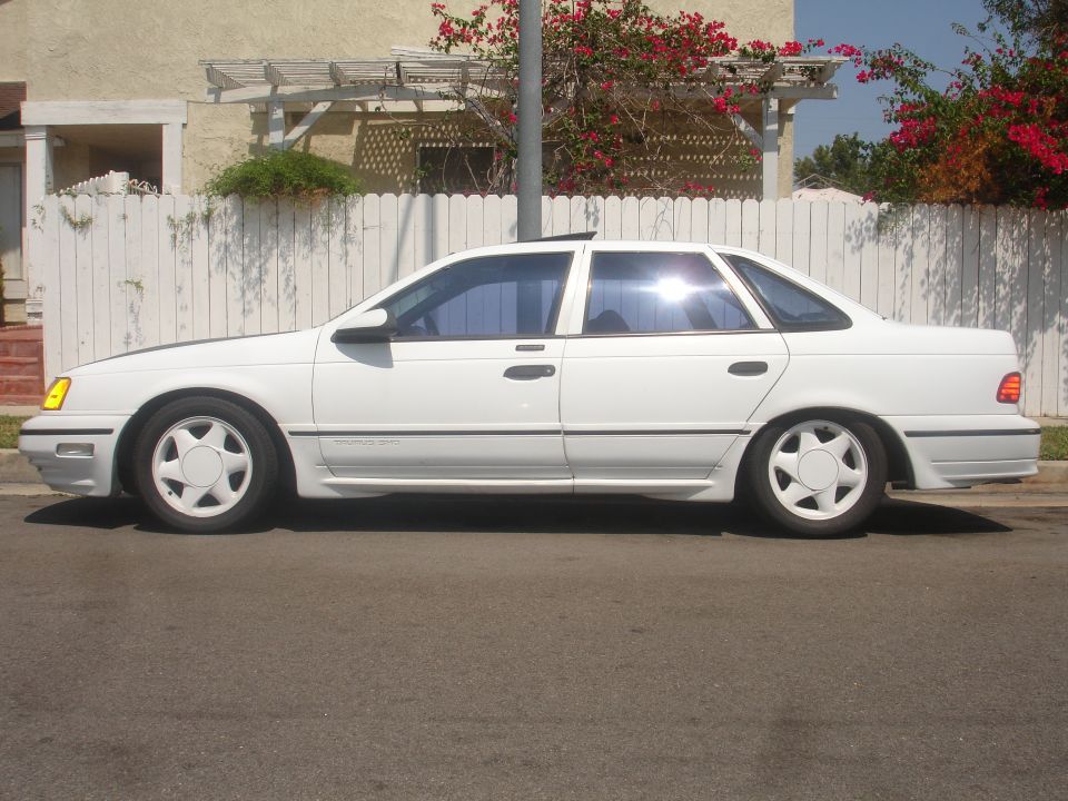 White Ford Taurus SHO sedan profile at the curb with white five-spoke wheels