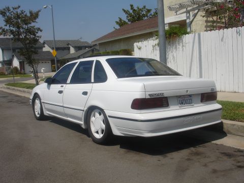 1990 Ford Taurus - Rear view of a white 1990 Ford Taurus SHO sedan parked curbside on a sunny day.