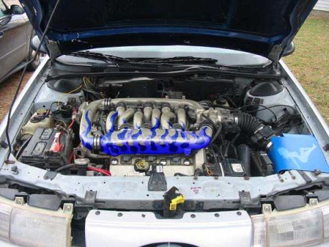 1998 Ford Taurus - Engine bay of a 1998 Ford Taurus, showing the V6 engine and custom blue intake piping.