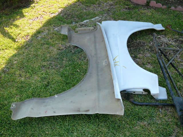 Two fenders, one fiberglass, one metal, on grass