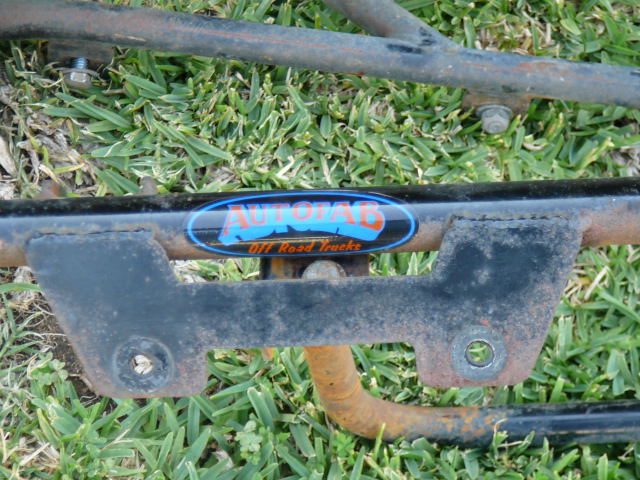 Metal frame part with Autofab Off Road Trucks logo. Rusty metal tubing and brackets visible
