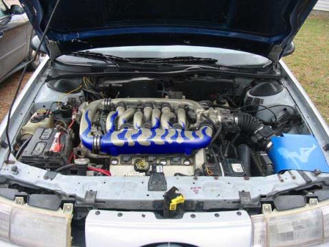 1998 Ford Taurus - The engine bay of a car is shown with the hood open, revealing the V6 engine and its components.