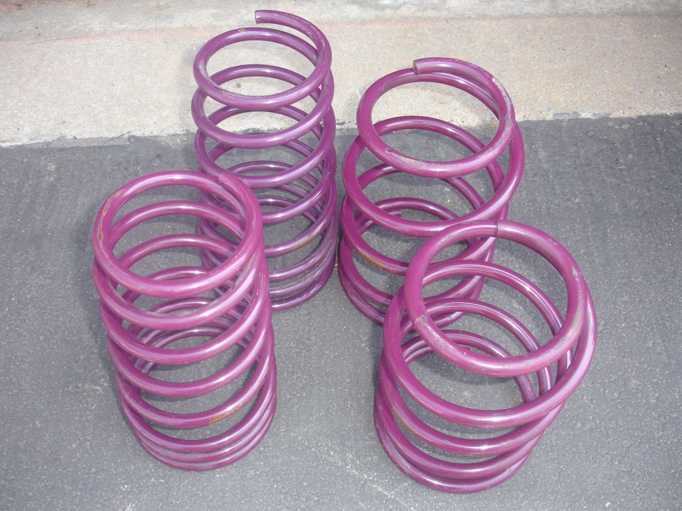 Four purple coil springs on a gray surface