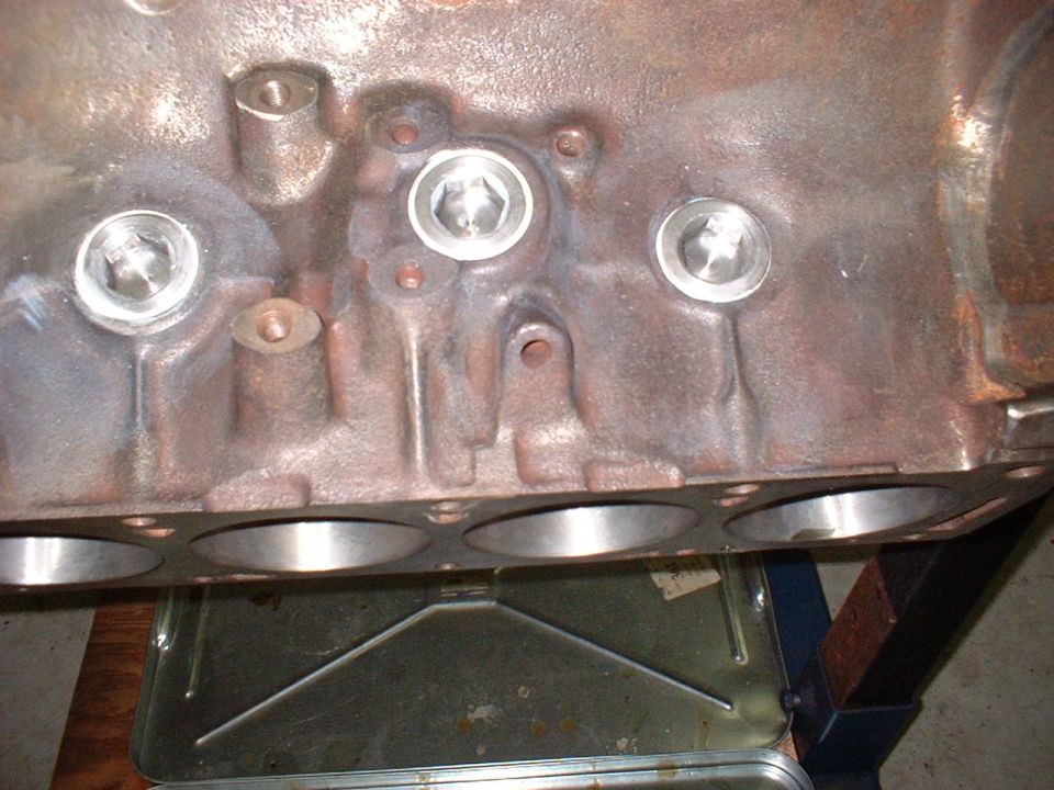 Close-up of a cast iron engine block with threaded plug holes.