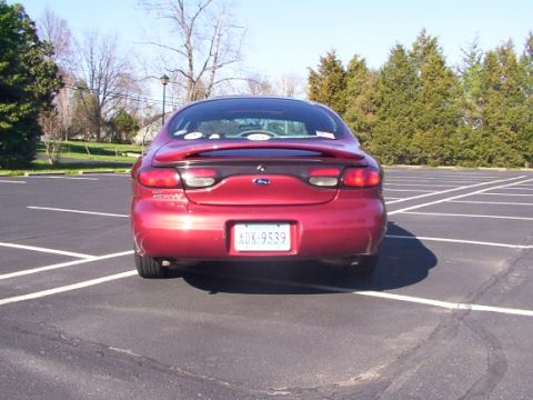 1998 Ford Taurus - Rear view of a red 1998 Ford Taurus sedan parked in an empty lot.