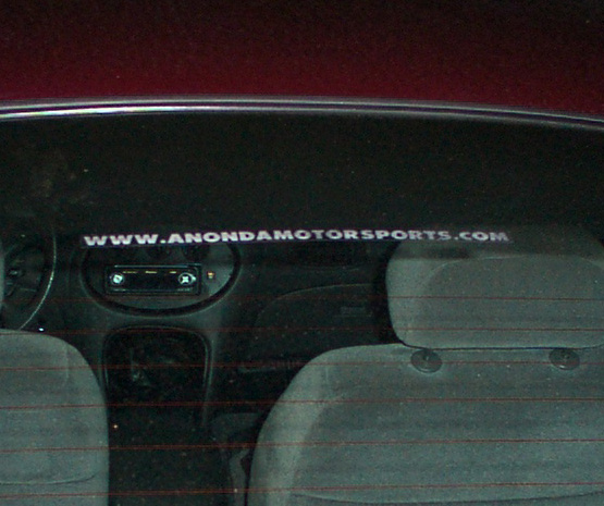 Interior view of a car showing seats, dashboard, and website stickers on the rear window