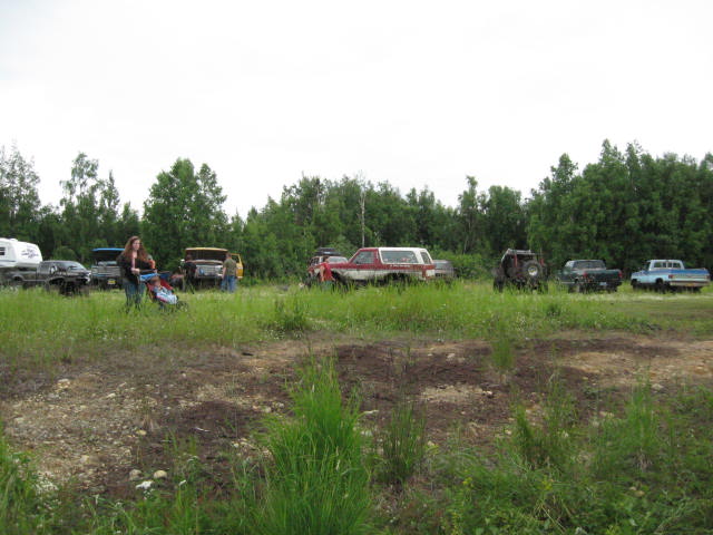 Woman with stroller in field with off-road vehicles and trucks