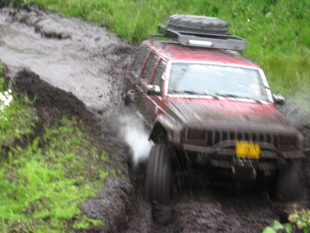 Red Jeep Cherokee off-roading through mud