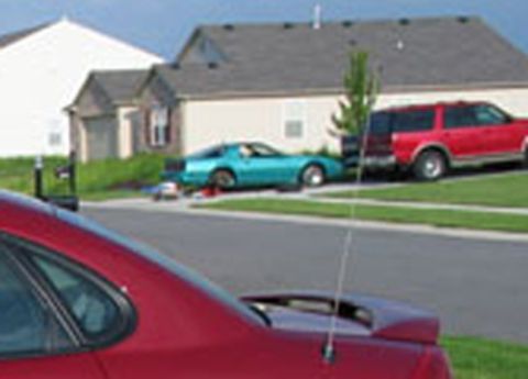 1998 Ford Taurus - Multiple vehicles are parked in a residential driveway with houses in the background.