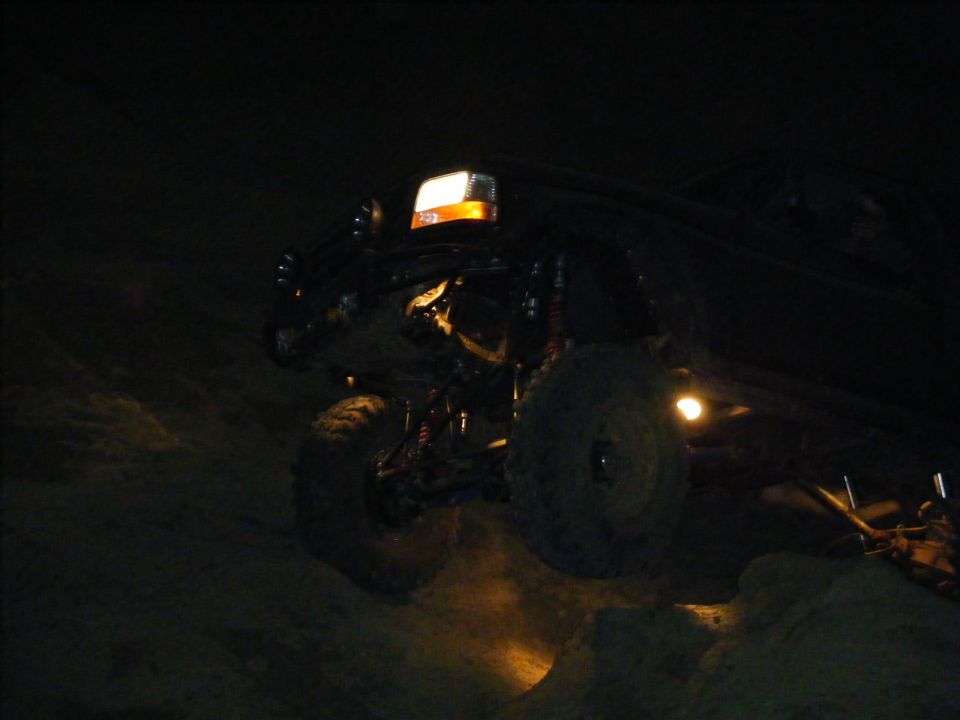 Underside of a lifted rock-crawler truck lit at night