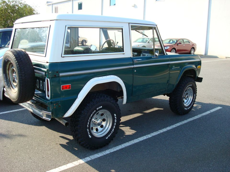 1977 Ford Bronco rear passenger side view, dark green with white hardtop, spare tire on rear door