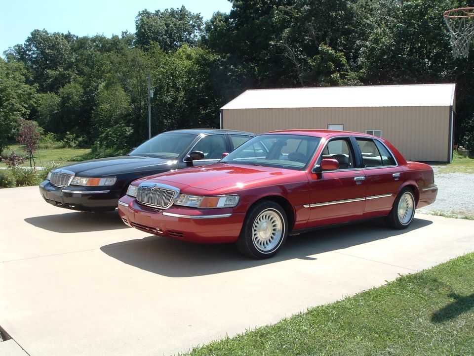 Two Mercury Grand Marquis sedans parked on a driveway.