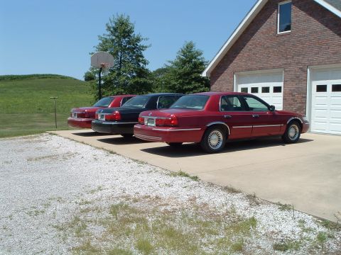 2001 Mercury Grand Marquis - Three 2001 Mercury Grand Marquis sedans are parked in a driveway on a sunny day.