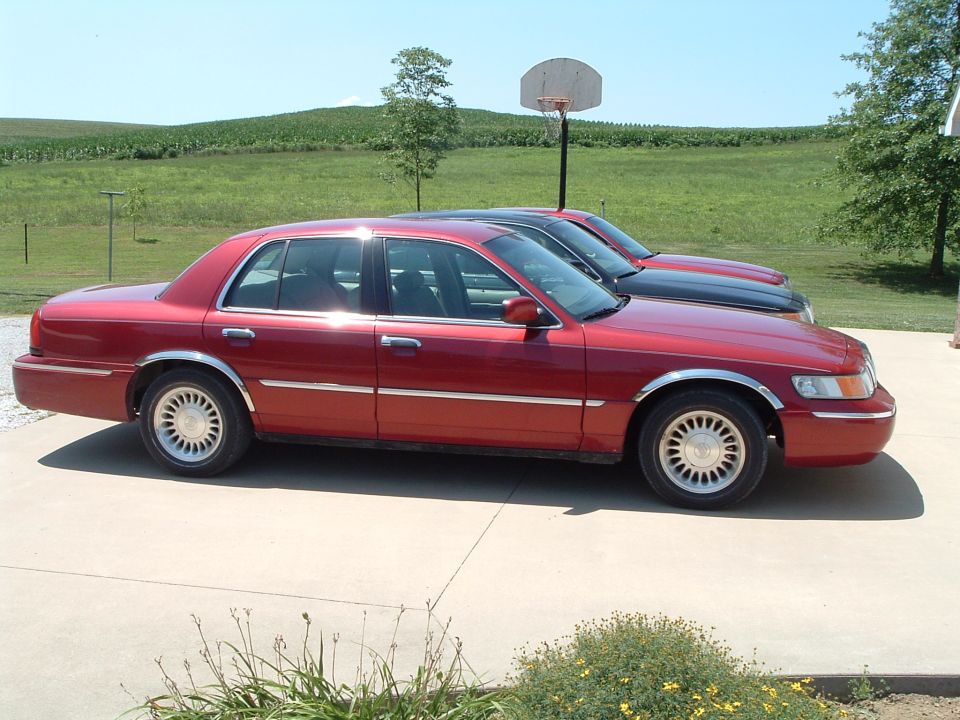 Red 2001 Mercury Grand Marquis sedan parked on concrete, side view