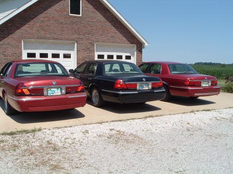 2001 Mercury Grand Marquis - Three 2001 Mercury Grand Marquis sedans are parked in a row in front of a brick garage.