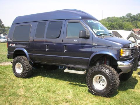 1995 Ford Bronco - This lifted van features oversized tires and a prominent grille guard, suggesting off-road capability.