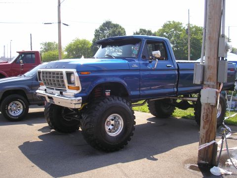 1995 Ford Bronco - This lifted blue Ford pickup truck, likely a 1979 model, is parked next to another vehicle.