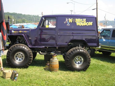 1995 Ford Bronco - A customized van, nicknamed the "Webble Wagon", sits on a grassy field with large off-road tires.
