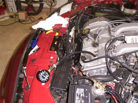 1998 Ford Taurus - Close-up of a vehicle's engine bay, a pressure gauge connected to the fuel system and a Ford emblem on the intake manifold.