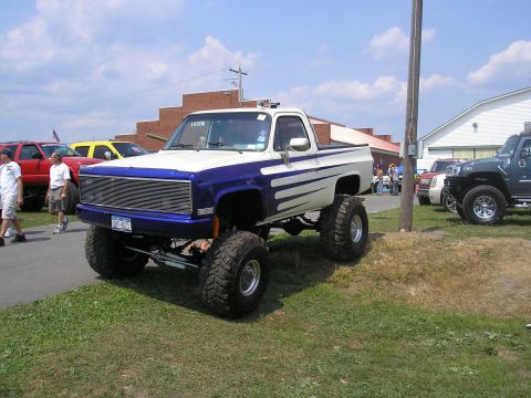 1995 Ford Bronco - Modified pickup truck with lifted suspension and custom paint job seen at an outdoor event.