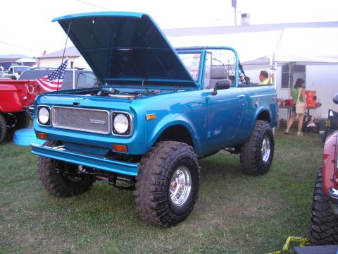 1995 Ford Bronco - A bright blue International Harvester Scout II is displayed with its hood open at an outdoor event.