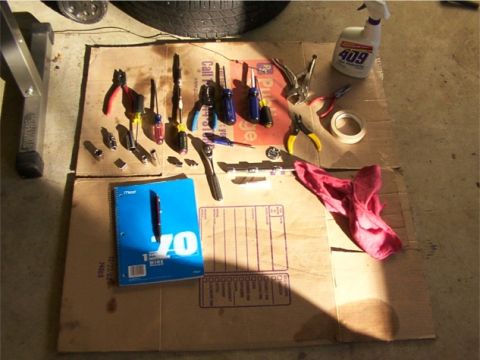 1998 Ford Taurus - Various tools, a notebook, and a rag are arranged on cardboard, suggesting a workspace for repairs or maintenance.