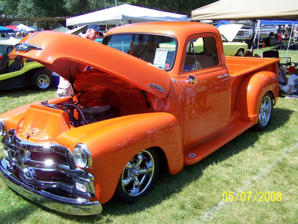 Orange classic pickup truck with hood open, chrome grille, and custom wheels.