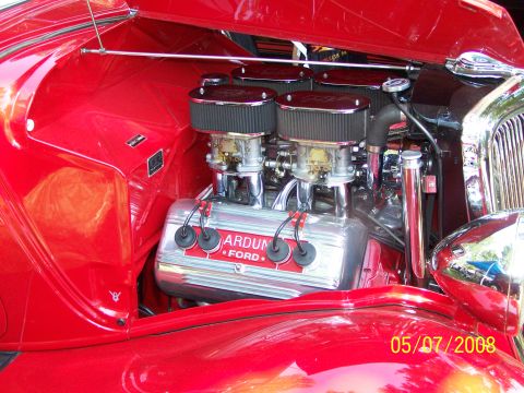 1973 Ford Mustang - Close-up view of a red classic Ford V8 engine with dual carburetors and chrome air cleaners. The engine block has "ARDUN FORD" text visible.