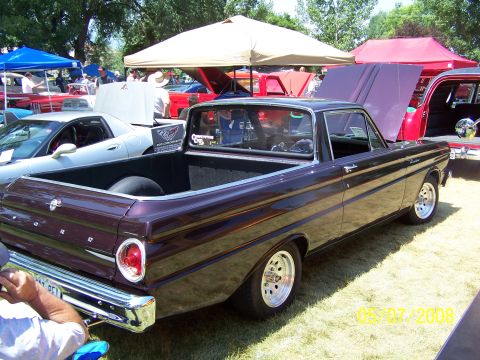 1973 Ford Mustang - A dark purple Ford Ranchero is parked on a grassy lawn at an outdoor car show. The vehicle is viewed from the rear quarter angle, showing i…