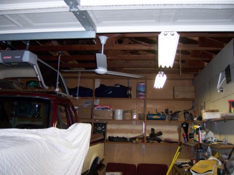1991 Ford Bronco - Photograph of a garage interior showing a ceiling fan, shelving, workbench, and a covered car.