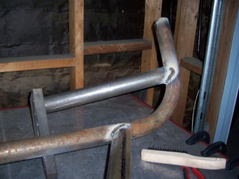 1991 Ford Bronco - Photograph of a fabricated steel tube part on a workbench, not a technical document.