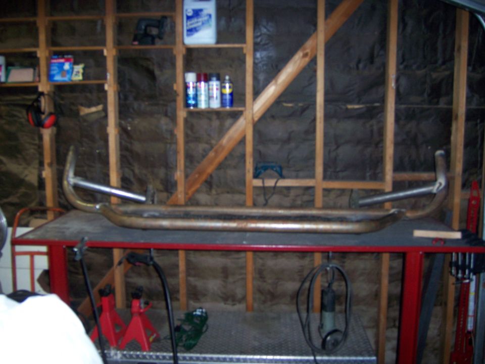 Tubular steel bumper hanging against a garage wall above jack stands