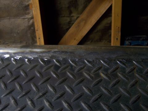 1991 Ford Bronco - Close-up of a textured metal surface with wooden structural elements in the background.