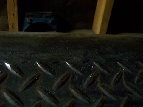 1991 Ford Bronco - Close-up view of a textured metal surface, possibly a vehicle part, with visible water droplets.