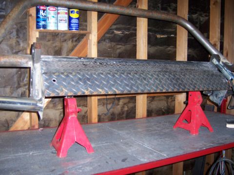 1991 Ford Bronco - A custom-fabricated metal bumper is supported by red jack stands in a workshop setting.
