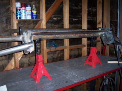 1991 Ford Bronco - A fabricated metal bumper assembly is supported by red jack stands in a workshop setting.