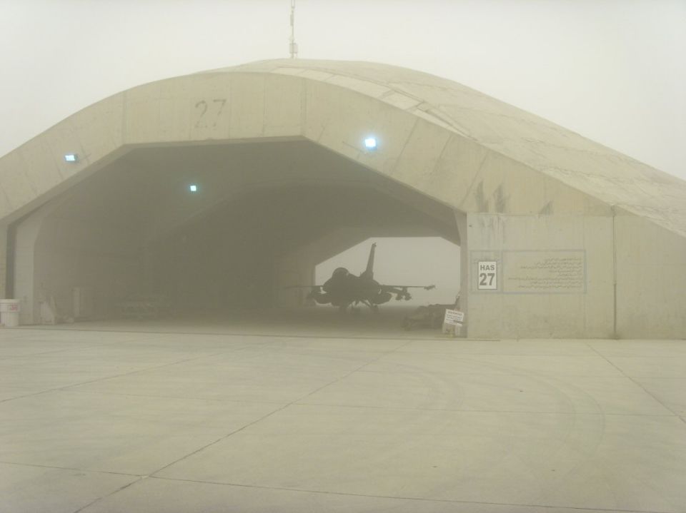 Concrete hardened aircraft shelter number 27 with a jet inside, dusty sky