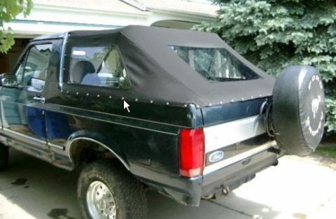 1995 Ford Bronco - Rear three-quarter view of a 1995 Ford Bronco a black soft top and external spare tire.