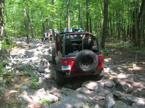 1996 Ford Bronco - Multiple Jeeps navigate a challenging rocky path through a dense forest.