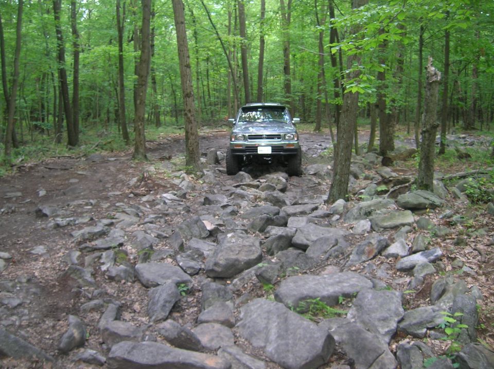 Green SUV navigating a rocky forest trail