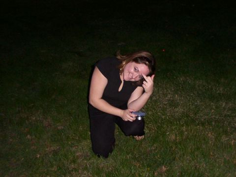 1998 Ford Taurus - A woman kneels in the grass at night, holding a camera and gesturing with her middle finger.