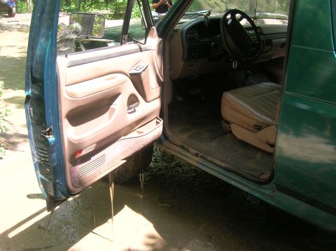 1996 Ford Bronco - Interior view of a 1996 Ford Bronco with the driver's door ajar, parked in a muddy area.