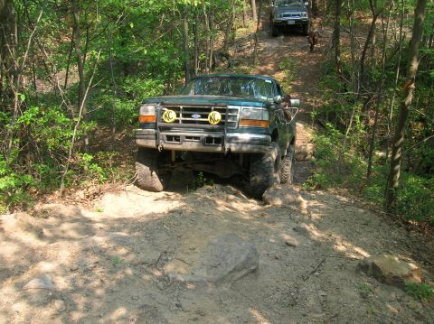 1996 Ford Bronco - A green 1996 Ford F-250 navigates a challenging off-road trail, with another vehicle visible further up the path.