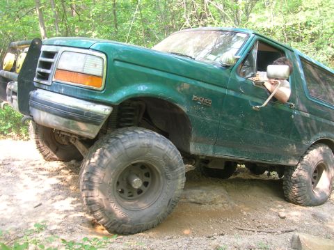 1996 Ford Bronco - 1996 Ford Bronco navigating rough terrain on a wooded trail.