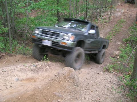 1996 Ford Bronco - A lifted pickup truck navigates a rocky off-road trail.