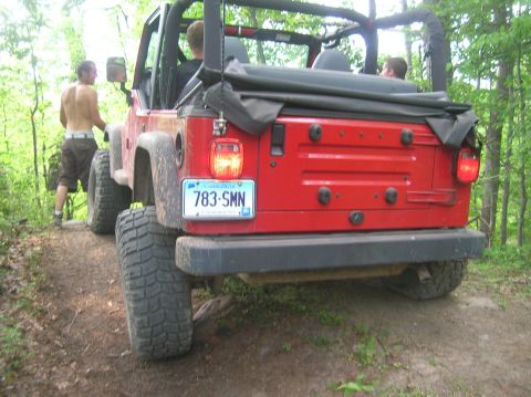 1996 Ford Bronco - Red Jeep Wrangler with large tires on a wooded trail. Connecticut license plate is visible.