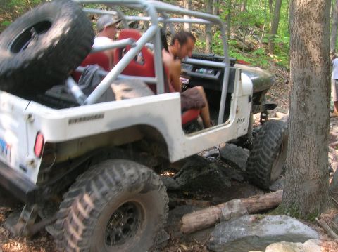 1996 Ford Bronco - Off-road Jeep Wrangler with roll cage and spare tire on roof, navigating rocky terrain.