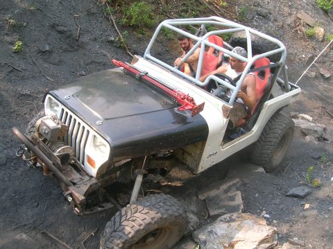 1996 Ford Bronco - A modified Jeep navigates a rocky, off-road trail with two occupants.