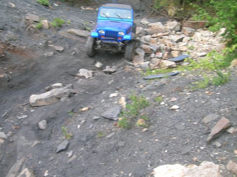 1996 Ford Bronco - A blue Jeep Wrangler navigates a rocky off-road trail.