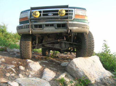 1996 Ford Bronco - This Ford truck navigates a challenging rocky terrain, its front grille clearly visible.